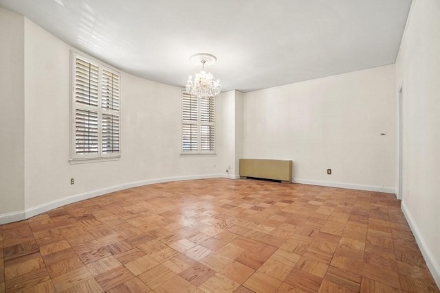 unfurnished room with baseboards and a chandelier