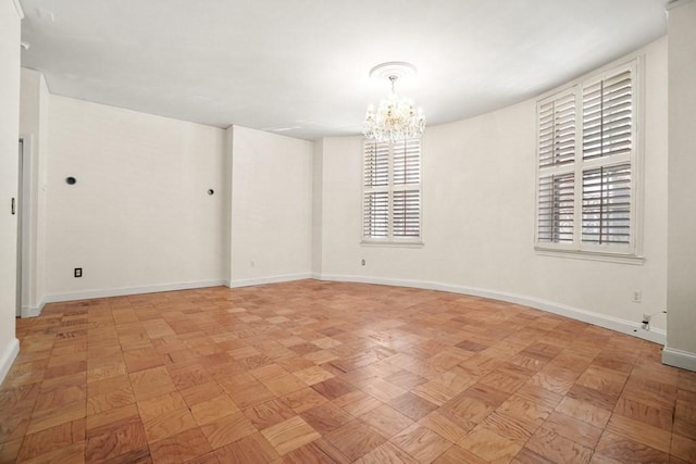 spare room with a chandelier and baseboards