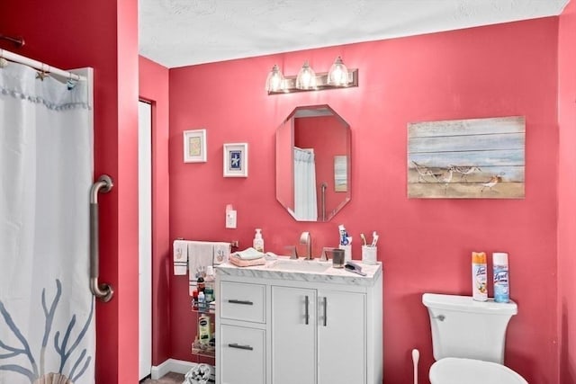 bathroom with a textured ceiling, vanity, and toilet