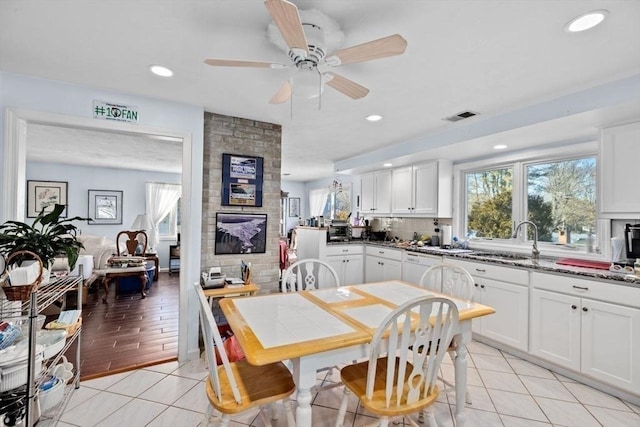 kitchen with dark stone counters, white cabinets, sink, ceiling fan, and light tile patterned floors