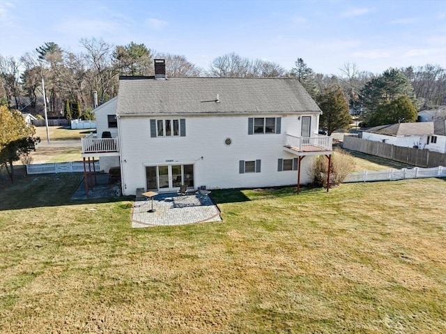 rear view of property featuring a lawn, a patio area, and a balcony