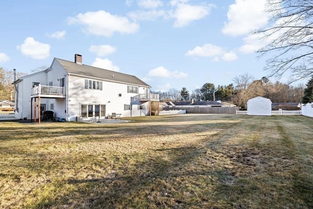 rear view of property with a yard, a balcony, and a storage unit