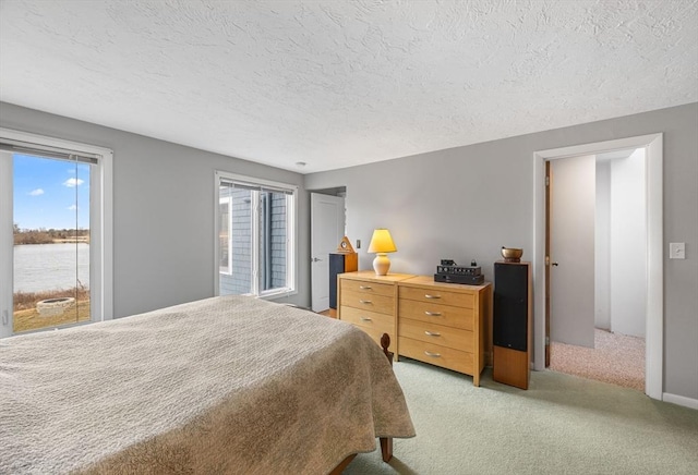 bedroom featuring a water view, light colored carpet, and a textured ceiling