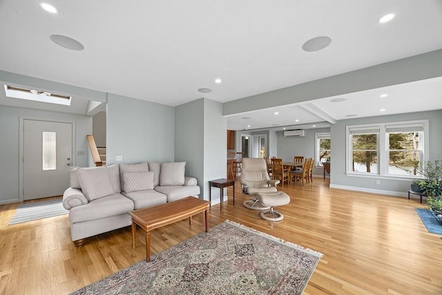 living room with stairway, baseboards, light wood finished floors, and a wall mounted AC