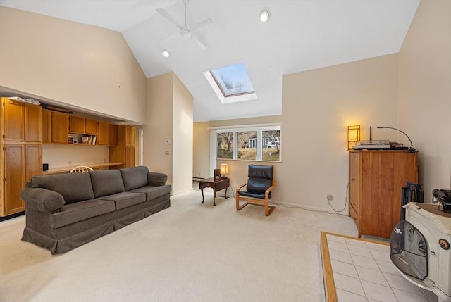 living room featuring high vaulted ceiling, light colored carpet, a skylight, and ceiling fan