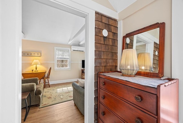 living area featuring light wood-type flooring, lofted ceiling, baseboards, and a wall mounted AC