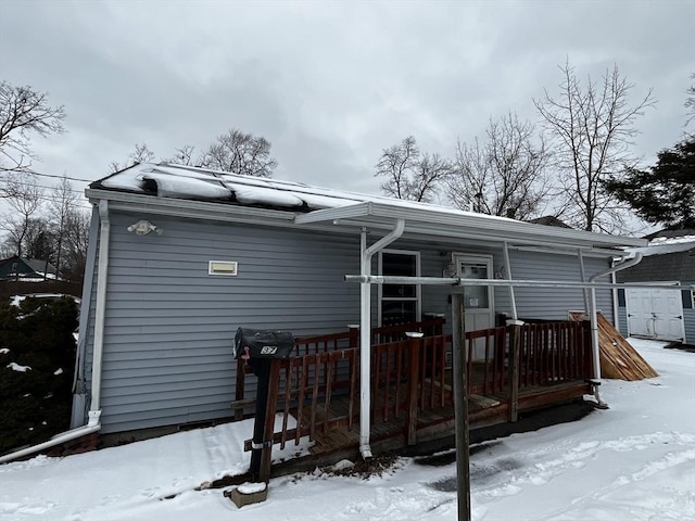 snow covered rear of property featuring a storage unit