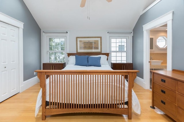 bedroom with lofted ceiling, multiple windows, a sink, and light wood finished floors