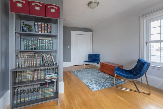 living area featuring vaulted ceiling, wood finished floors, and baseboards