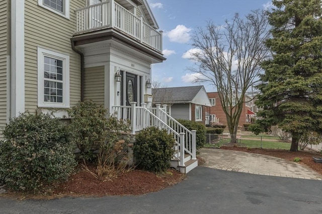view of side of home with fence and a balcony