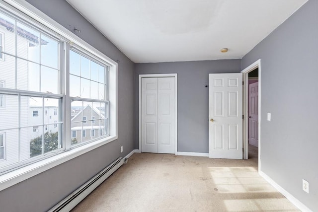 unfurnished bedroom featuring a closet, light colored carpet, baseboards, and baseboard heating