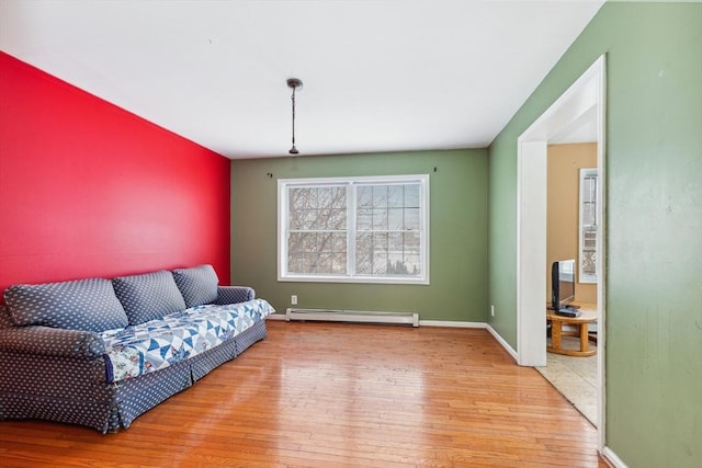 living area featuring baseboard heating, baseboards, and hardwood / wood-style floors