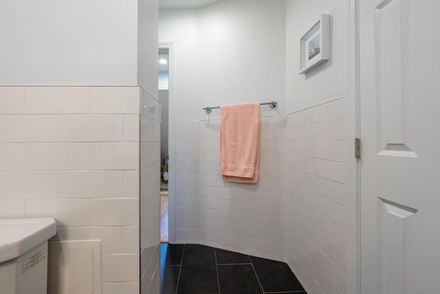 bathroom featuring vanity, wainscoting, tile patterned flooring, and tile walls