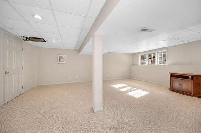 basement with a paneled ceiling and light carpet