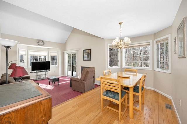 dining room featuring an inviting chandelier, light hardwood / wood-style flooring, and lofted ceiling