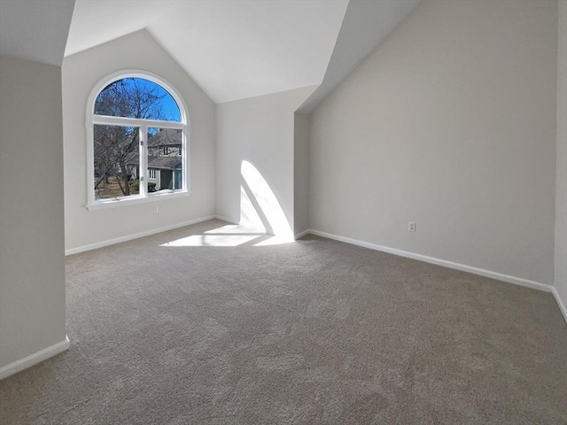 carpeted spare room featuring baseboards and lofted ceiling