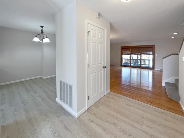 hall with stairway, wood finished floors, visible vents, baseboards, and a notable chandelier