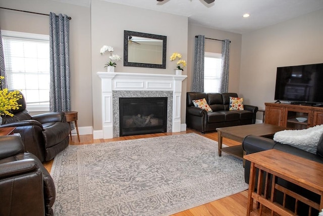 living area with ceiling fan, recessed lighting, baseboards, light wood finished floors, and a glass covered fireplace