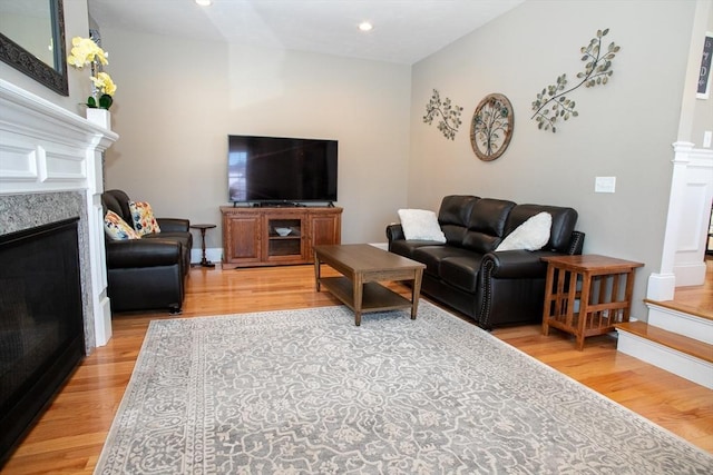 living area featuring a high end fireplace, decorative columns, light wood-style flooring, and recessed lighting