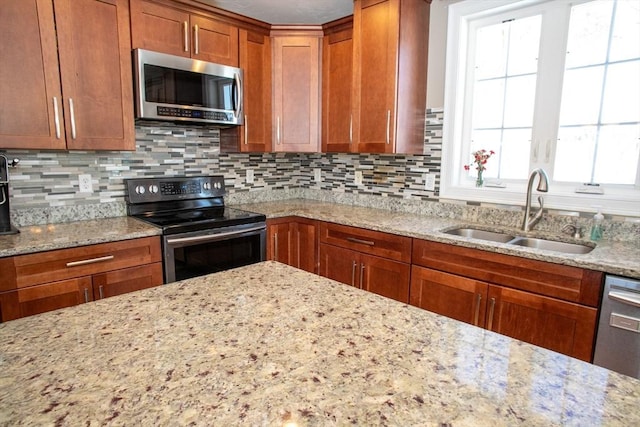 kitchen featuring light stone countertops, backsplash, stainless steel appliances, and a sink