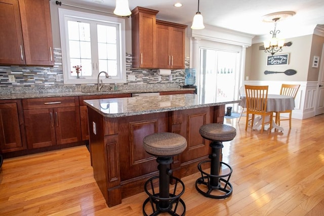 kitchen featuring light wood finished floors, decorative backsplash, brown cabinets, and a sink