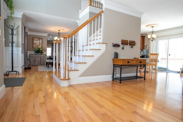 foyer entrance featuring light wood-style floors, crown molding, and a notable chandelier