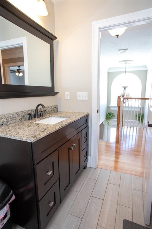 bathroom featuring ceiling fan with notable chandelier, vanity, visible vents, and wood finish floors