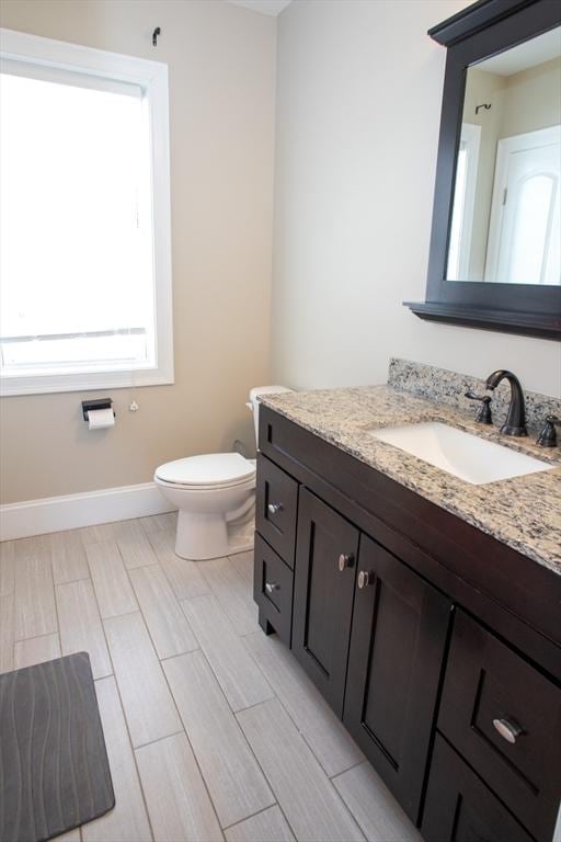 bathroom featuring wood finish floors, baseboards, vanity, and toilet