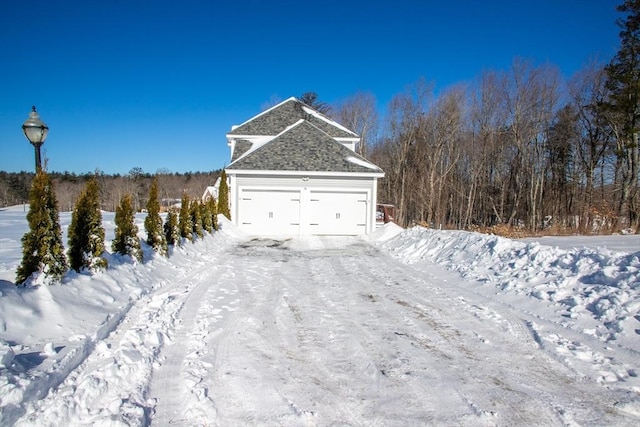 view of snowy exterior featuring a shingled roof and an attached garage