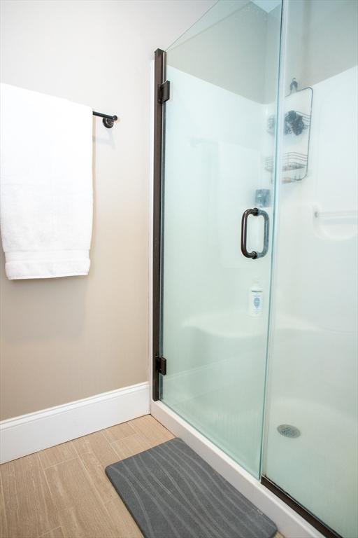 bathroom featuring a shower stall, baseboards, and wood finished floors