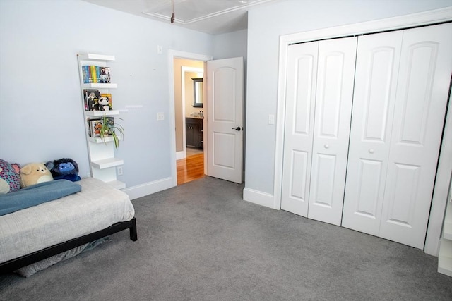 carpeted bedroom featuring attic access, baseboards, and a closet