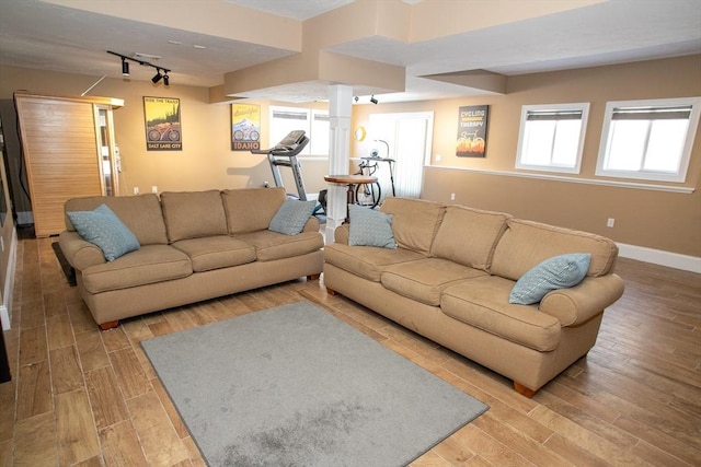 living area with light wood-type flooring, rail lighting, and baseboards