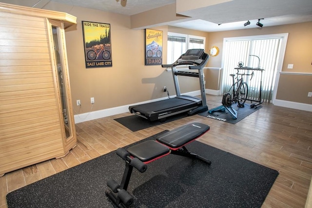 exercise area featuring baseboards and wood finished floors