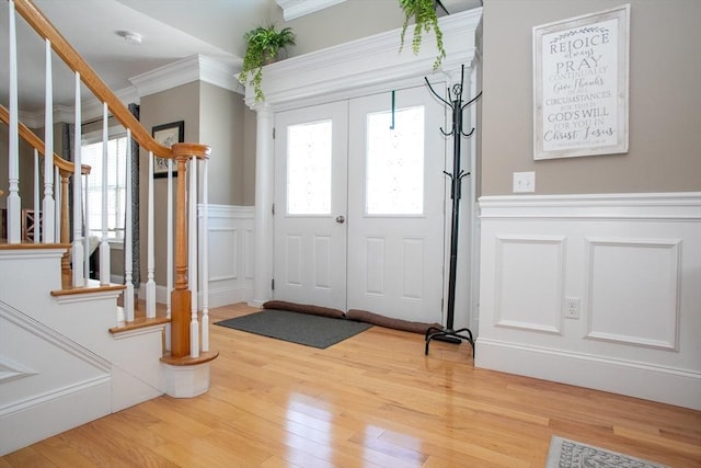 foyer entrance with ornamental molding, a healthy amount of sunlight, light wood-style flooring, and stairs