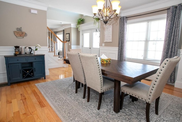 dining space featuring light wood-style floors, stairway, wainscoting, and crown molding