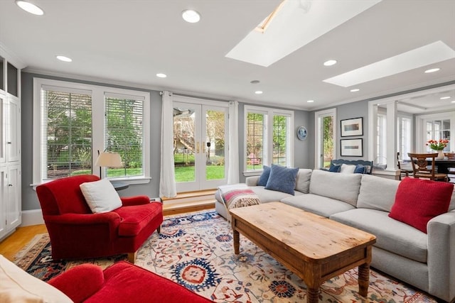 living room featuring crown molding, french doors, recessed lighting, light wood-type flooring, and a skylight