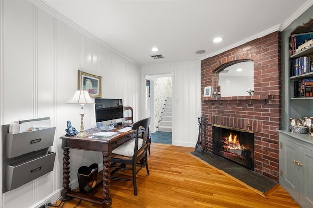 office featuring crown molding, a fireplace, light wood-style flooring, recessed lighting, and visible vents