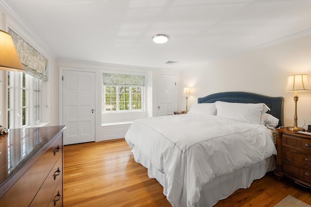 bedroom with light wood-style floors and crown molding