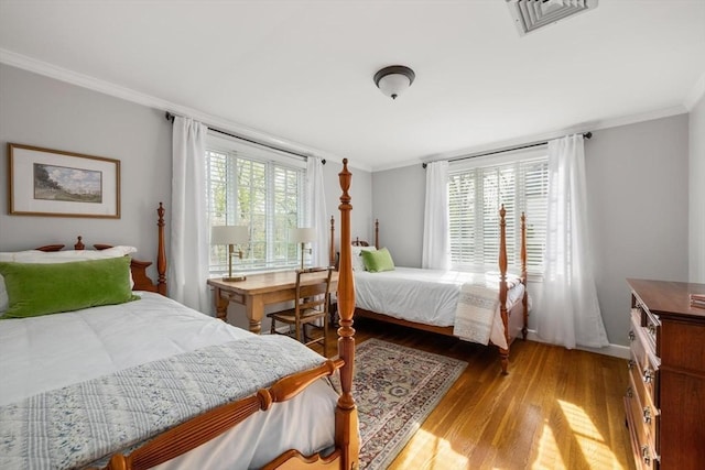bedroom featuring baseboards, visible vents, ornamental molding, and light wood-style flooring