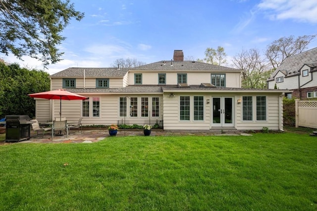 back of property with fence, a chimney, french doors, a patio, and a yard