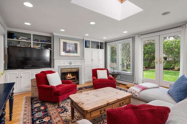 living area with a high end fireplace, a baseboard heating unit, french doors, light wood-style flooring, and a skylight
