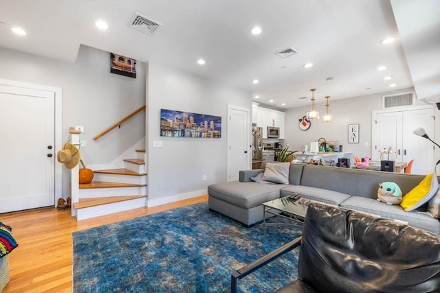 living area with light wood-type flooring, stairway, recessed lighting, and baseboards