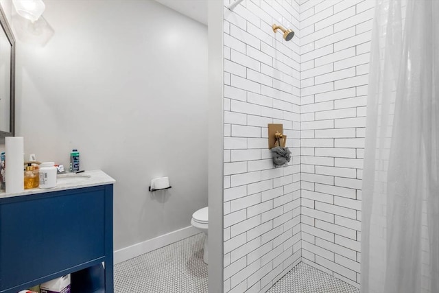 bathroom with a stall shower, toilet, vanity, tile patterned floors, and baseboards
