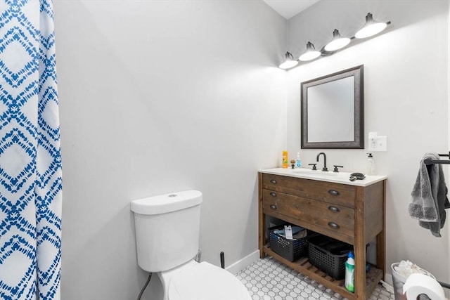 bathroom featuring toilet, vanity, and baseboards