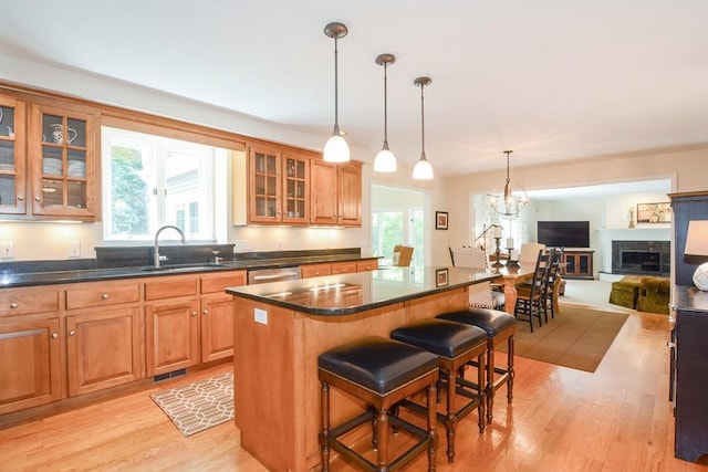 kitchen with a center island, a fireplace with raised hearth, brown cabinetry, open floor plan, and a kitchen breakfast bar