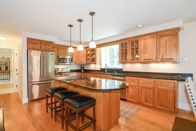 kitchen featuring brown cabinets, light wood finished floors, a kitchen bar, and stainless steel appliances