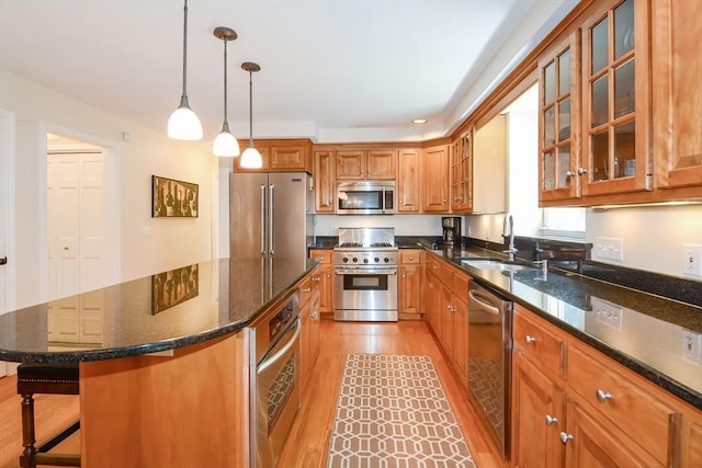 kitchen featuring brown cabinetry, light wood-style flooring, high quality appliances, a center island, and a sink