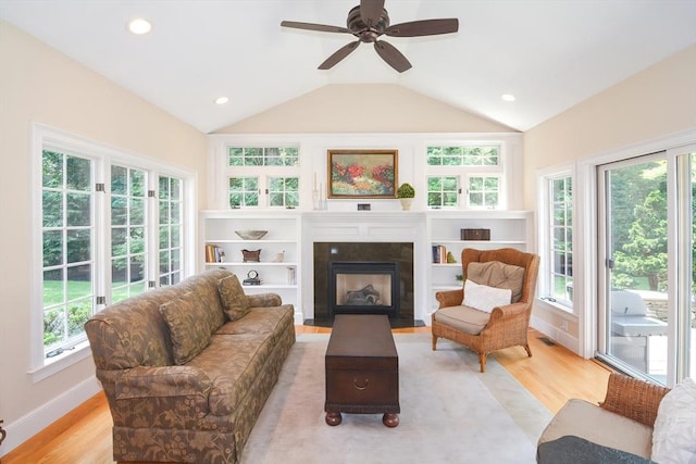 living room featuring lofted ceiling, visible vents, a fireplace with flush hearth, and light wood-style flooring