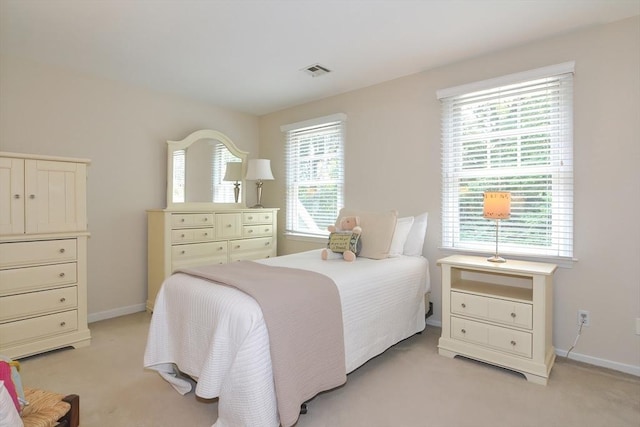 bedroom with multiple windows, visible vents, and light colored carpet