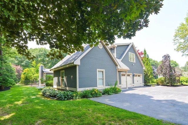 exterior space with an attached garage, a shingled roof, fence, driveway, and a yard